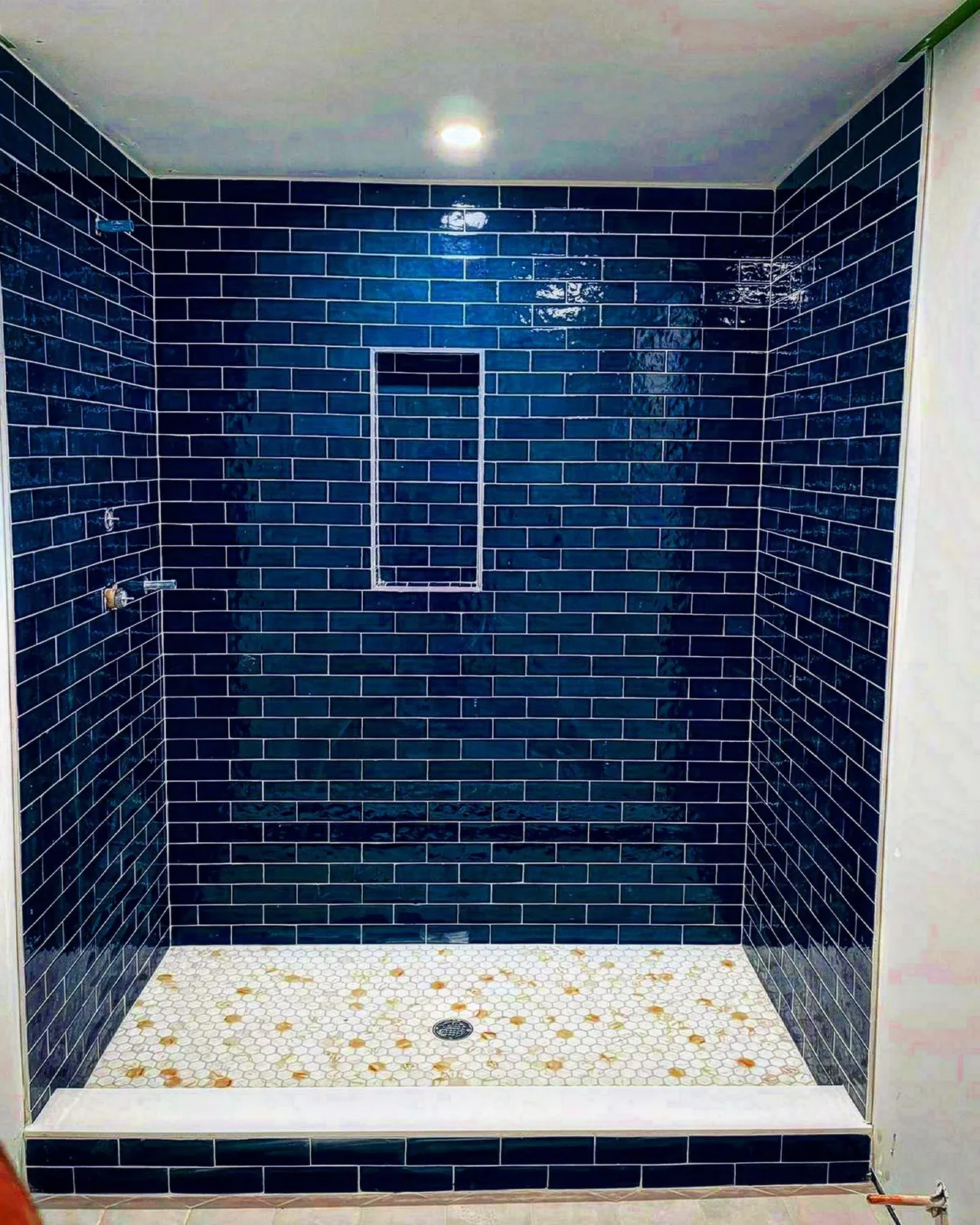 Blue subway tile shower with honeycomb floor