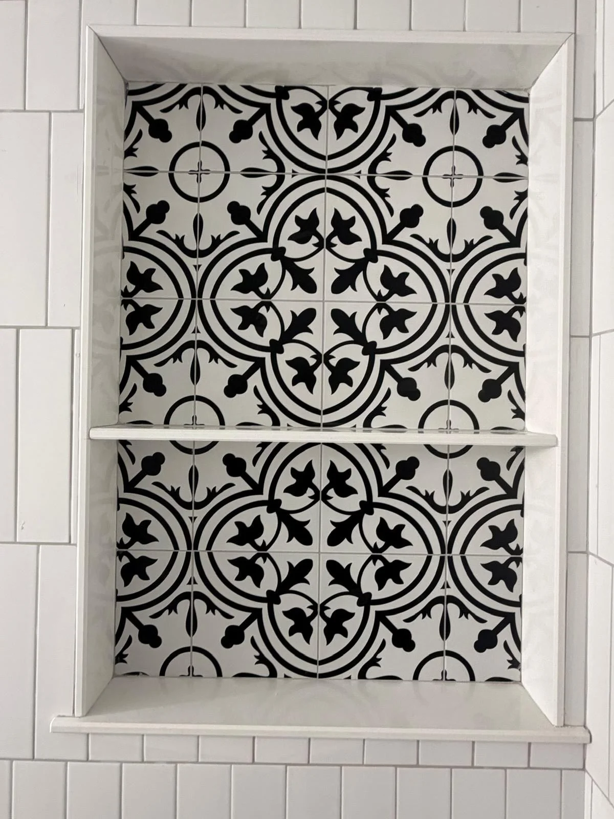Black and white patterned tile niche with white subway tile surround and shelf. by Vicentino Ceramic Tile in Blue Bell, PA