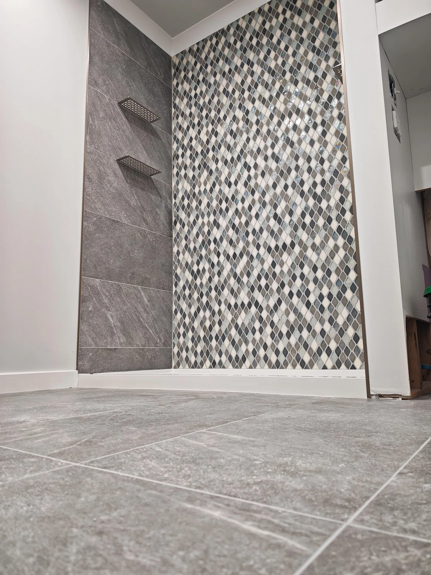 Modern shower with gray large-format tile wall and decorative mosaic tile accent wall. by Vicentino Ceramic Tile in Blue Bell