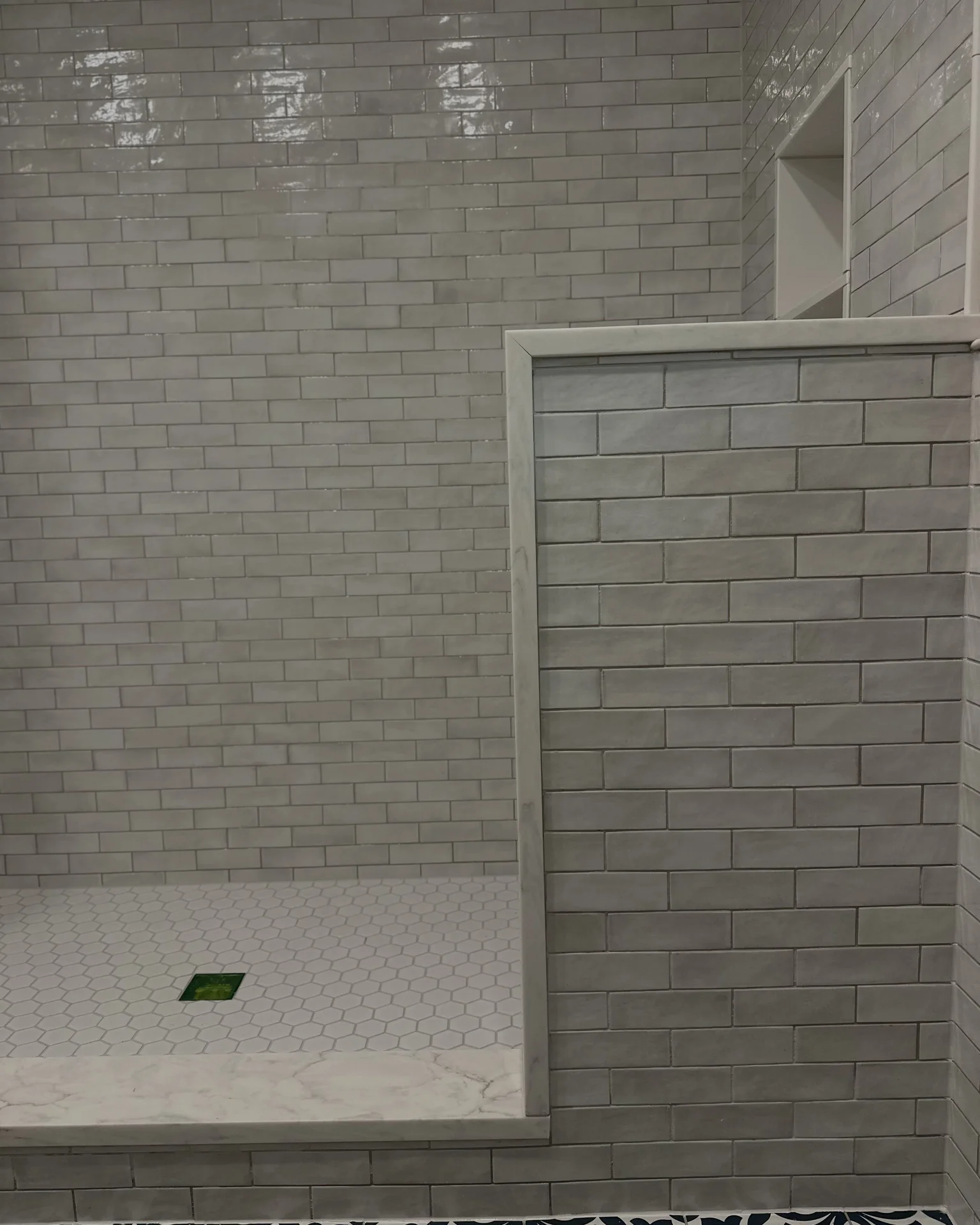 Modern shower with light gray subway tile walls and white hexagonal floor tiles. by Vicentino Ceramic Tile in Haddonfield, NJ