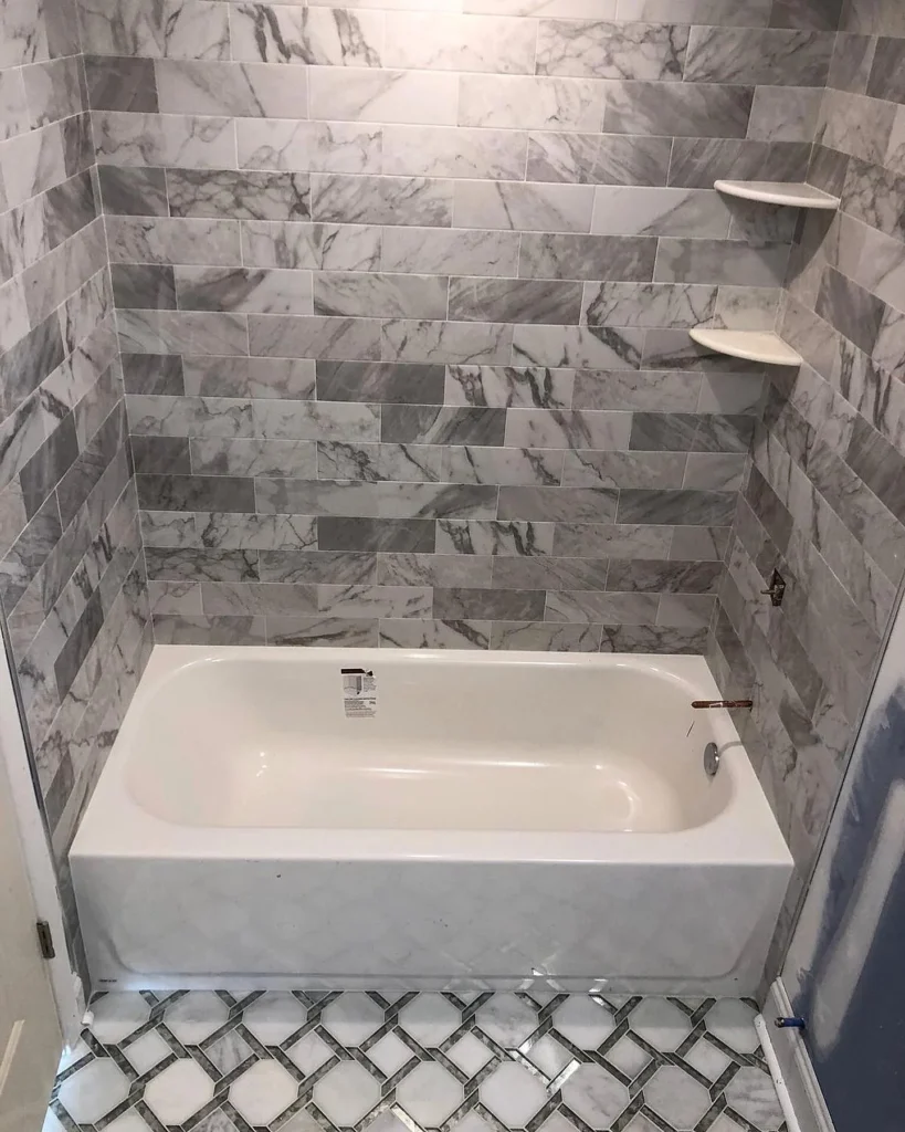 New bathtub and shower walls with gray and white marble subway tile. by Vicentino Ceramic Tile in Bryn Mawr, PA