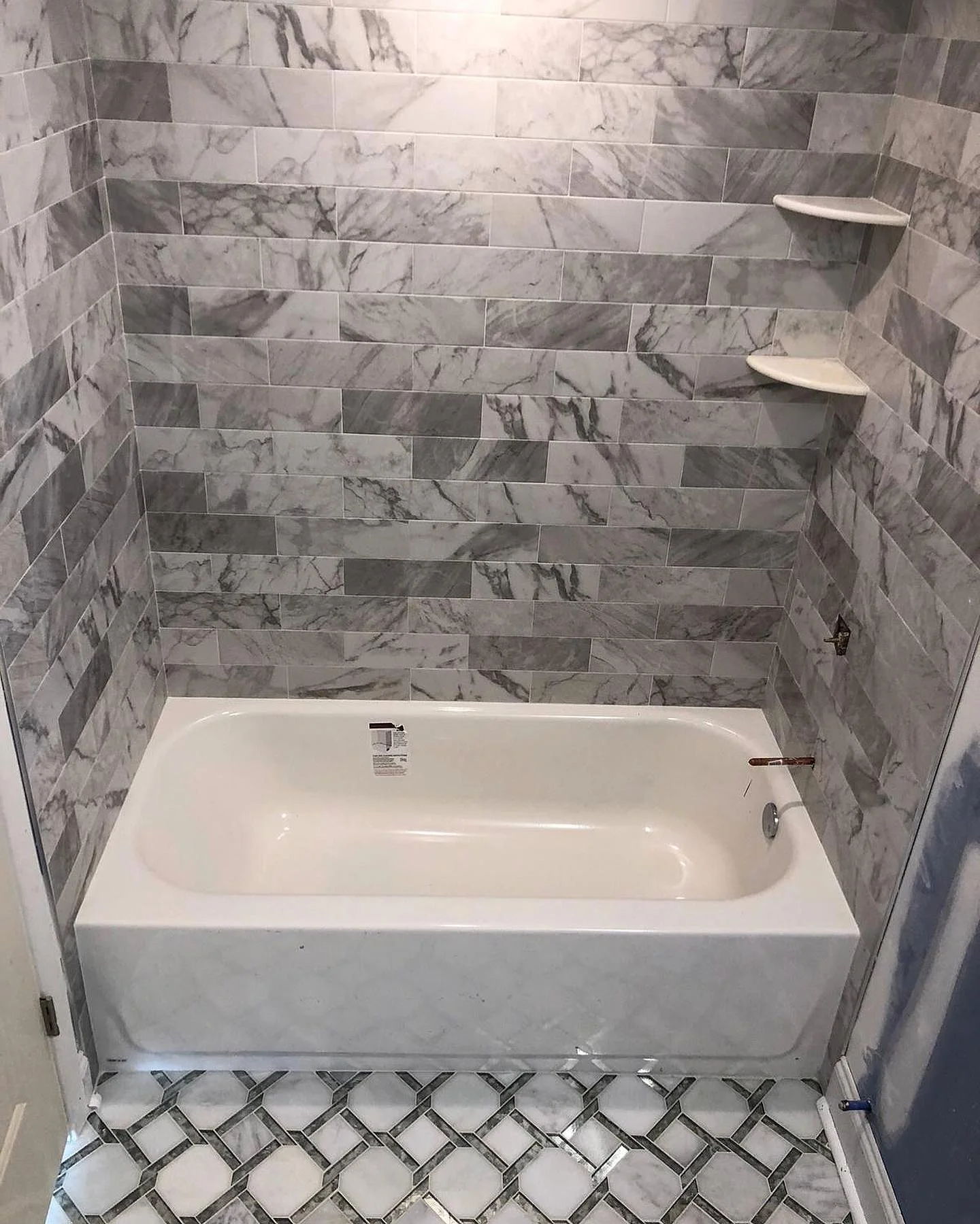New bathtub and shower walls with gray and white marble subway tile. by Vicentino Ceramic Tile in Bryn Mawr, PA