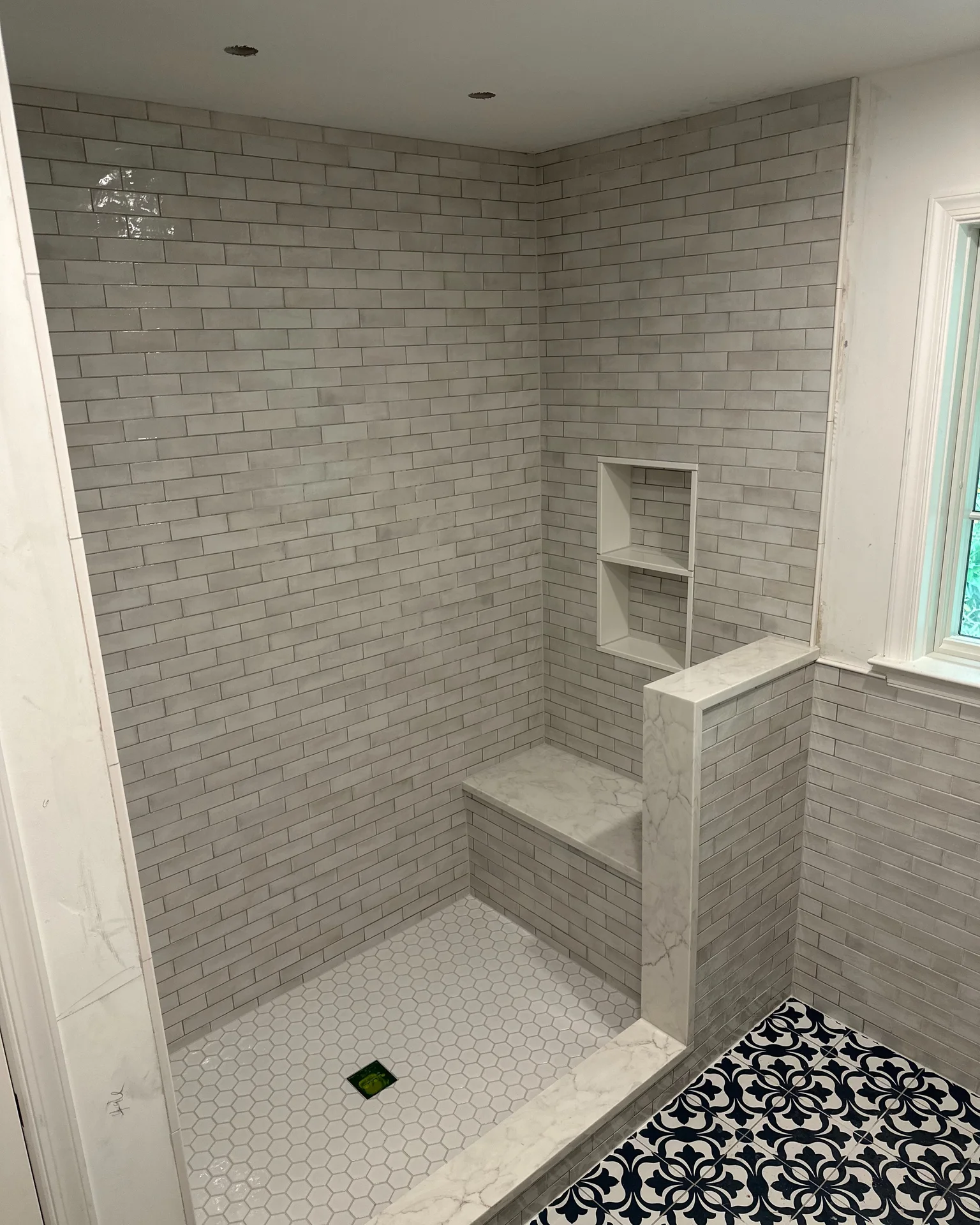 Newly tiled shower with gray subway tiles, white hexagonal floor, and decorative by Vicentino Ceramic Tile in Yardley, PA