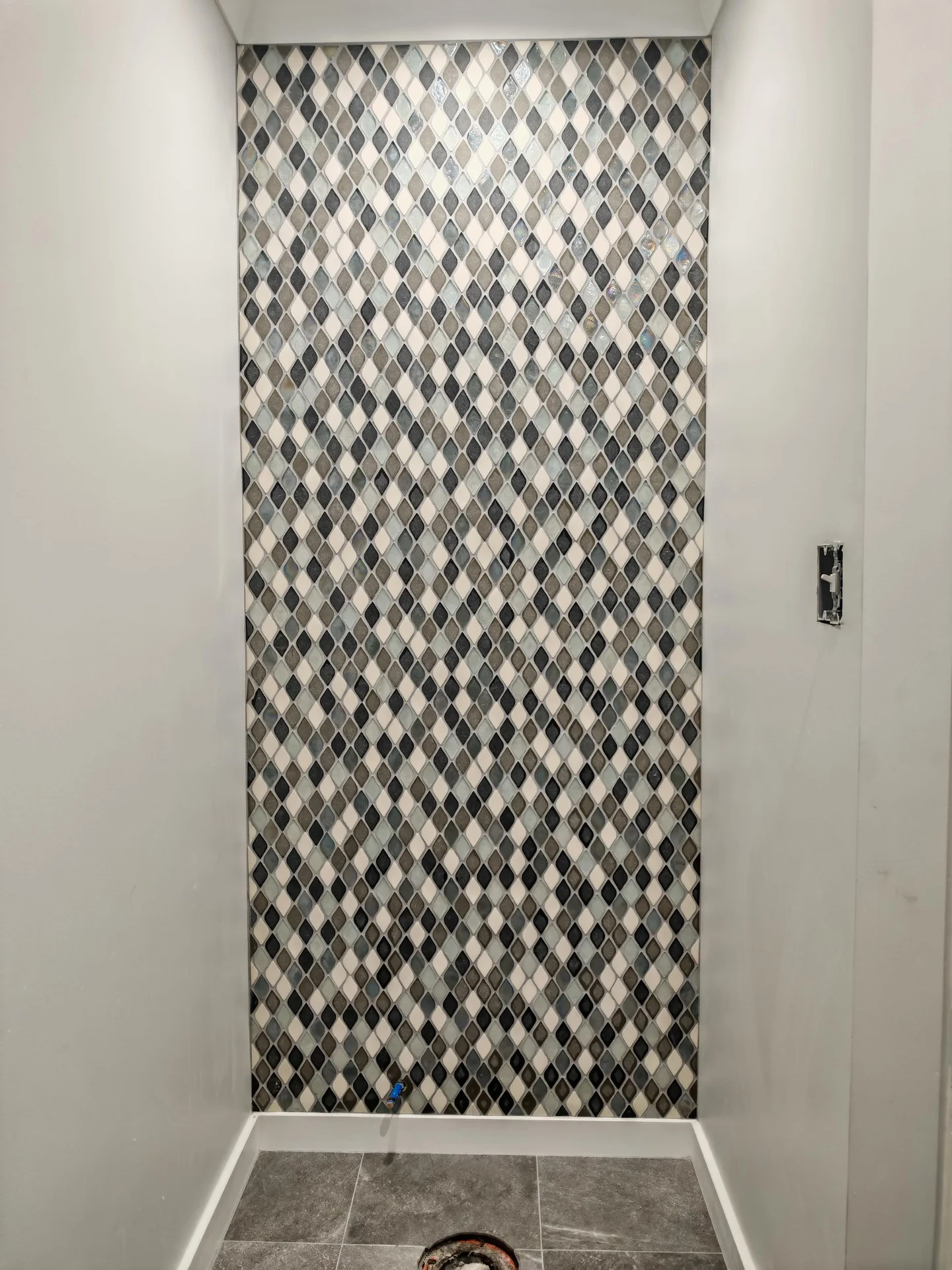Shower wall with decorative mosaic tile in teardrop pattern, gray floor tile. by Vicentino Ceramic Tile in Huntingdon Valley,