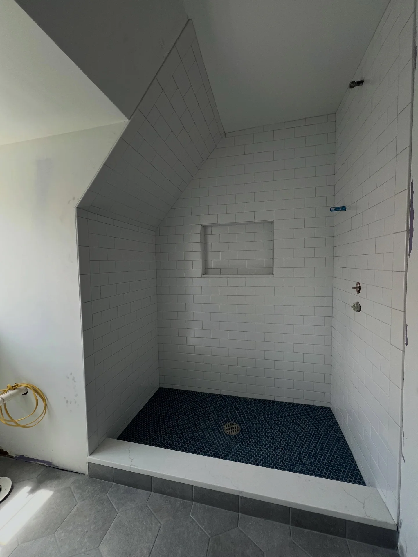 White subway tile shower with dark blue penny tile floor and built-in niche. by Vicentino Ceramic Tile in Haddonfield, NJ