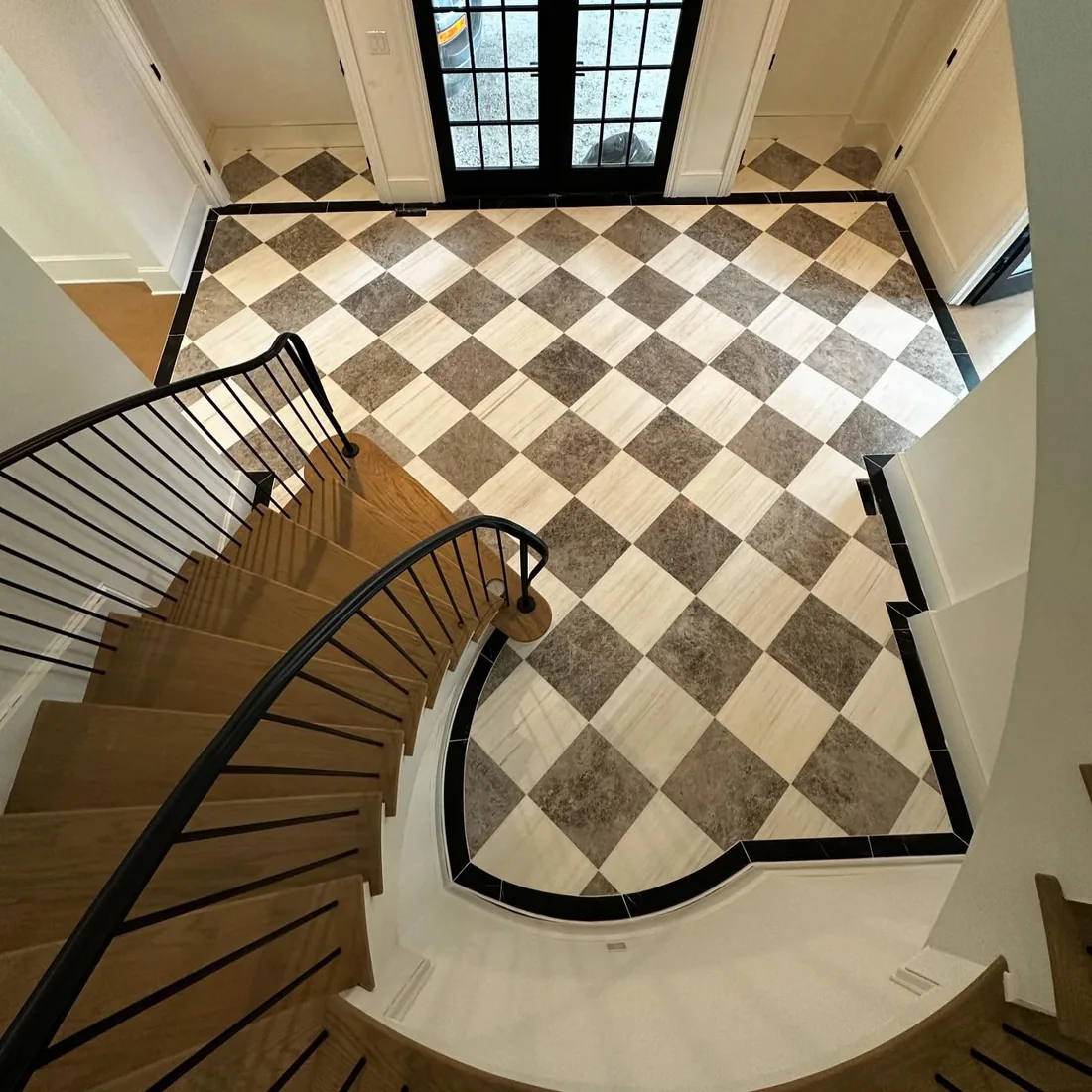 Checkered tile floor with black border and wooden stairs.