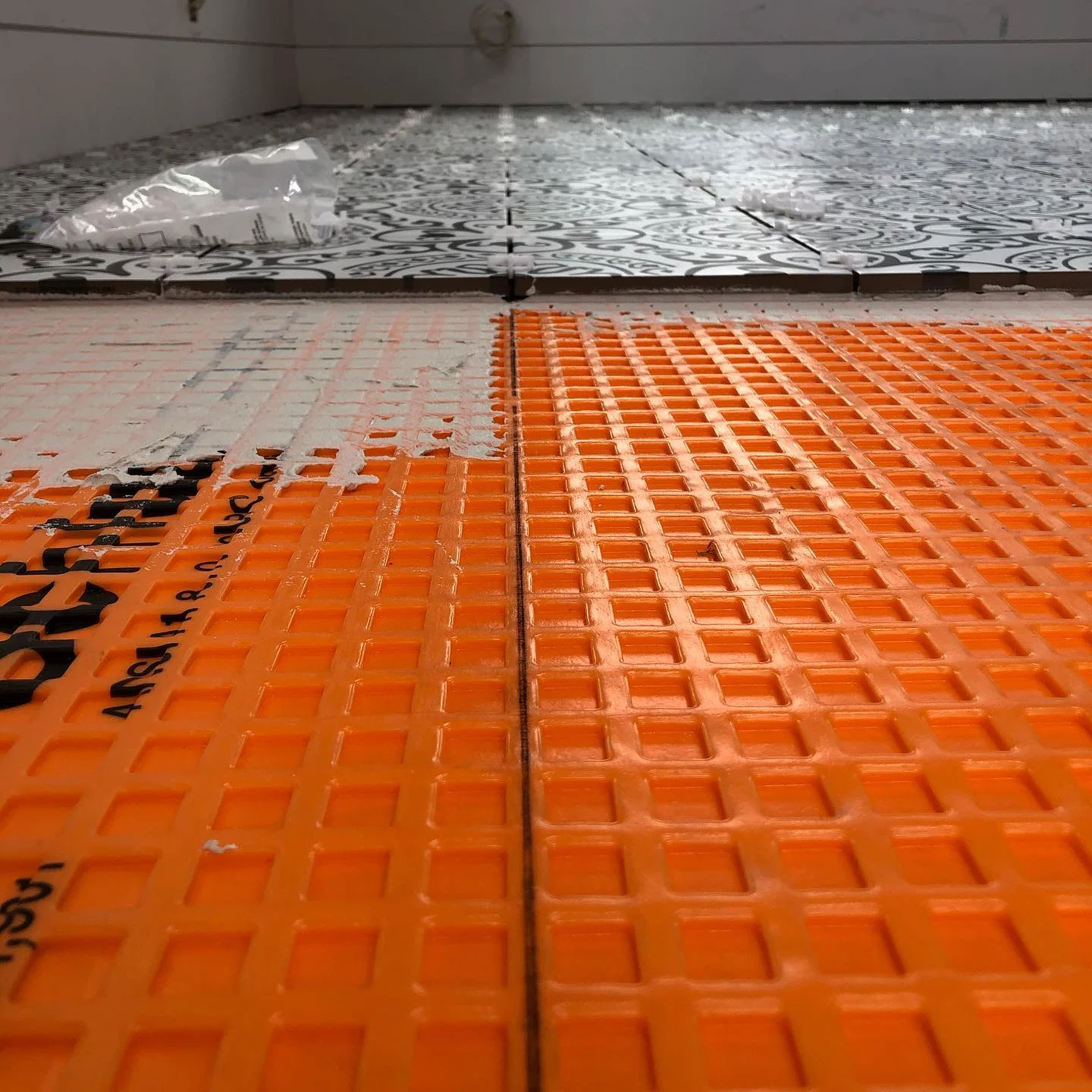 Close-up of orange schluter ditra matting being installed with white by Vicentino Ceramic Tile in Huntingdon Valley, PA