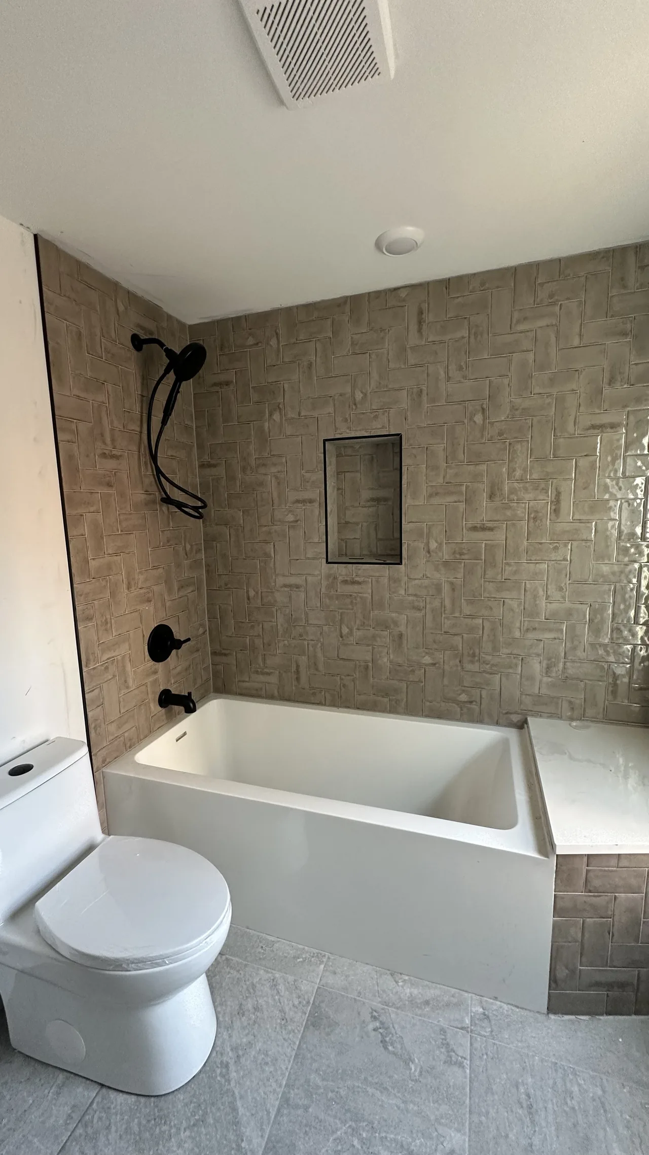 Bathroom with herringbone tile shower and new tub