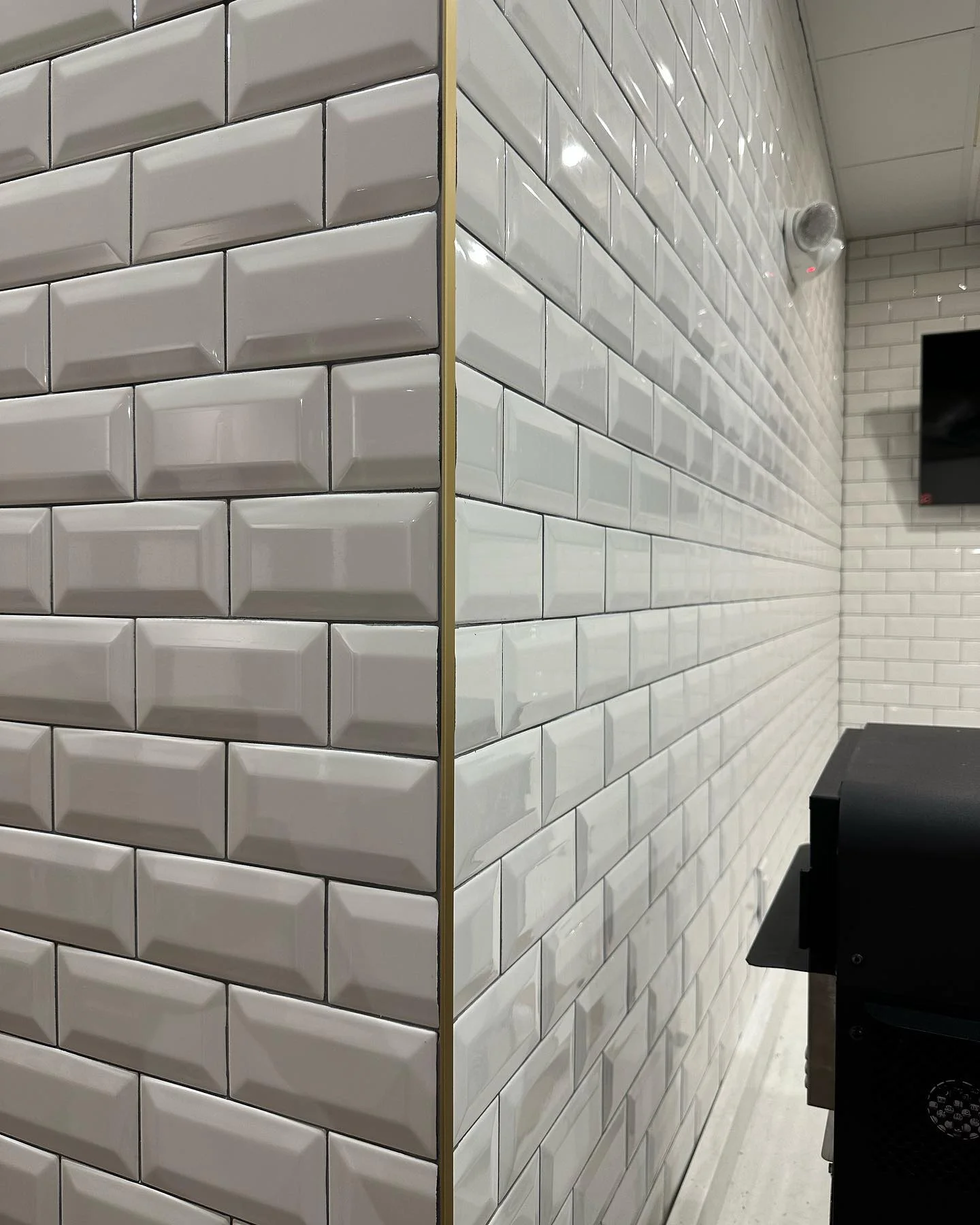 Crisp white subway tile walls with a decorative gold trim corner accent. by Vicentino Ceramic Tile in Haddonfield, NJ