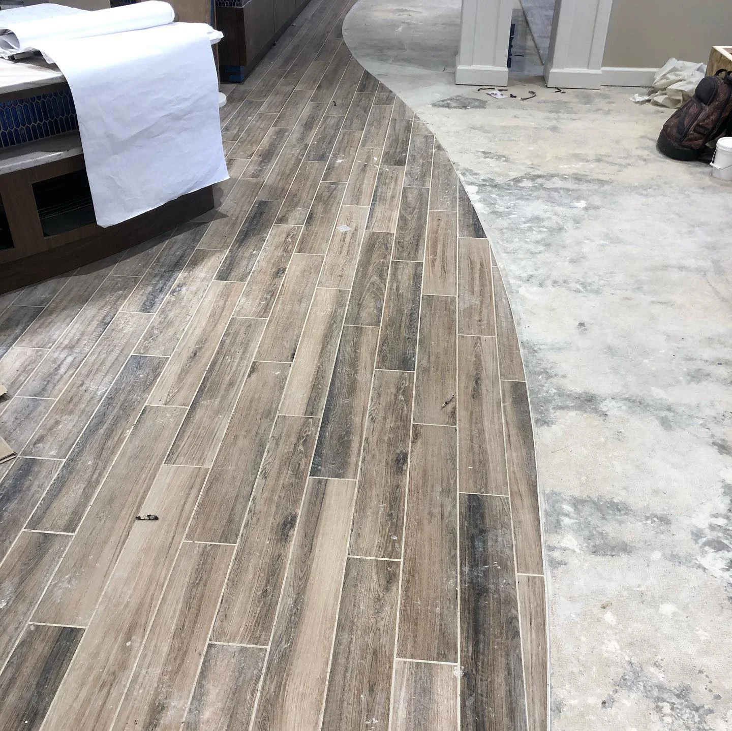 New wood-look tile flooring installed with a curved edge in a residential space. by Vicentino Ceramic Tile in Ambler, PA