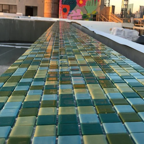 Close-up of small green and blue mosaic tiles on an outdoor wall or ledge. by Vicentino Ceramic Tile in Yardley, PA