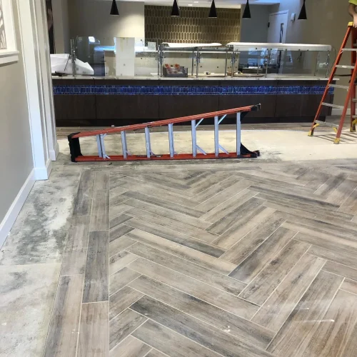Wood-look tile flooring in a herringbone pattern with blue mosaic wall tile. by Vicentino Ceramic Tile in Wayne, PA